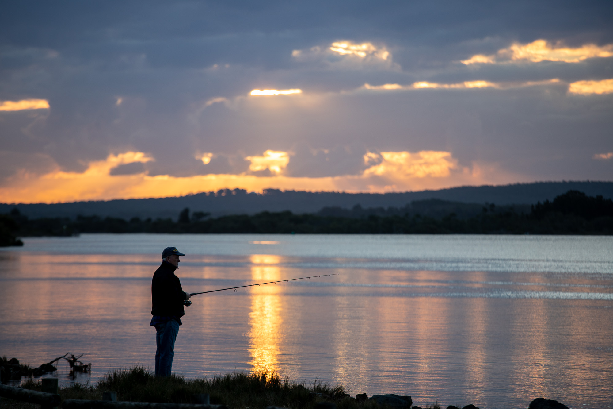 Fisherman silhouetted against the setting sun using a fast shutter speed